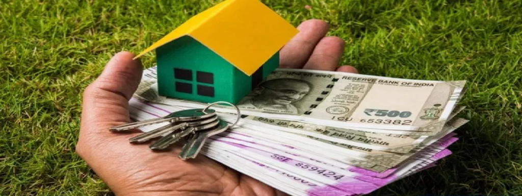 a hand holding a money, home key, and small house